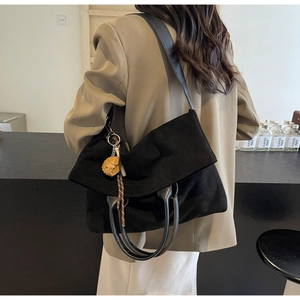 Détail du grand sac cabas en daim noir avec pendentif boule jaune sur la bandoulière chic