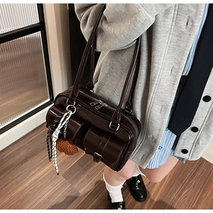 Détail du sac à bandoulière en cuir verni marron foncé avec poches et breloque en peluche