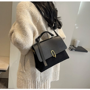 Detail of black crossbody bag with gold U-buckle and elegant suede texture contrast