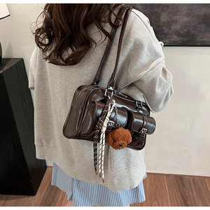 Détail du sac oreiller en similicuir marron foncé avec boucles et breloque chien