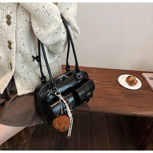 Detail of black retro pillow bag with front flap pockets and cute bear charm pendant