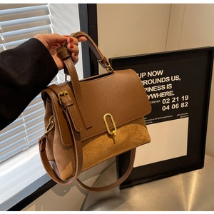 Detail of brown contrast patchwork handbag with gold oval metal clasp and smooth leather