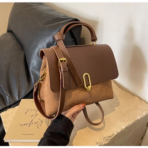 Detail of retro dual-texture leather handbag featuring elegant gold U-shaped metal clasp
