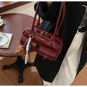 Détail du sac à main brillant rouge foncé avec multipoches et pendentif ours en peluche