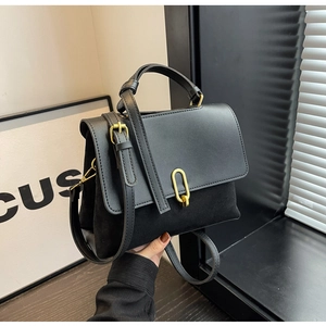 Detail of black matte and suede patchwork handbag with a golden oval clasp and top handle