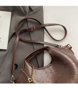 Close-up of vintage brown leather bucket bag with golden chain and adjustable strap