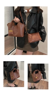 Detail view of dark brown faux leather bucket bag with gold chain and matching pouch