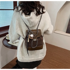 Close-up of brown matte mini backpack featuring chain straps and baseball-themed charms