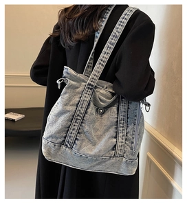 Detail of washed denim tote bag showing metal side zipper and distressed fabric texture