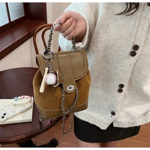 Detail view of brown matte leather handbag featuring chain handle and baseball charms