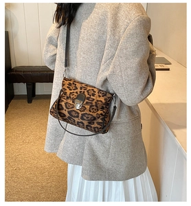 Detail of leopard print crossbody bag with metal lock and slim strap on shoulder