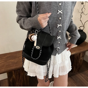 Detail of matte black chain bucket bag with silver clasp and sports theme pendants