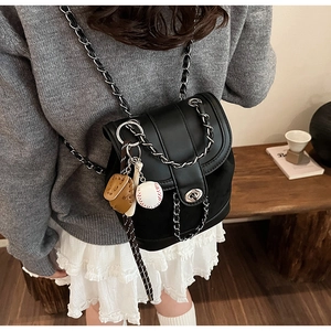 Close-up of black matte mini backpack with silver chain straps and baseball charms