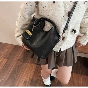 Détail du sac seau noir avec porte-monnaie à chaîne dorée et bandoulière réglable