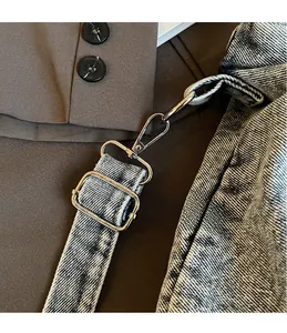 Detail of silver metal hooks and adjustable buckle on vintage washed denim tote bag