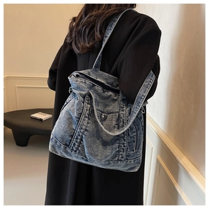 Detailed side view of washed denim tote bag with functional pockets on female model