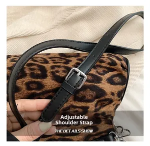 Detail of adjustable black faux leather strap with silver buckle on leopard print bag