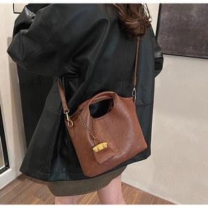 Detail of caramel brown bucket bag with gold chain lock and retro leather texture