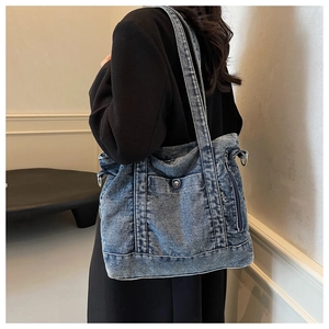 Detail of blue denim tote bag showing multiple pockets and retro stitching for casual look
