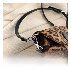 Detailed view of the silver metal hook and leather strap on a leopard print handbag