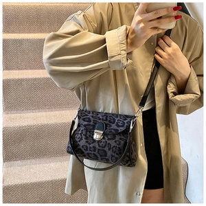 Leopard print crossbody bag with silver buckle worn over a beige trench coat