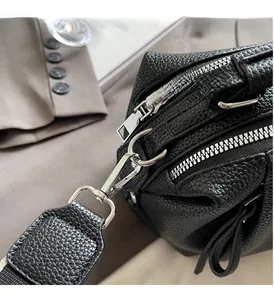 Close-up of black lychee grain leather bag with silver metal zippers and D-rings