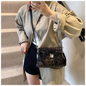Detail view of retro leopard print crossbody bag with silver clasp on beige trench coat