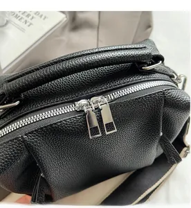 Close-up of smooth silver dual metal zippers on black lychee grain leather bag