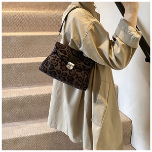 Detail of leopard print crossbody bag featuring silver metal lock and textured fabric