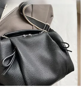 Detail of black pebble leather Boston bag with bicolor fabric strap and silver hardware