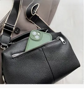 Close-up of black lychee grain leather boston bag with functional front zipper pocket