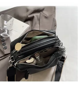 Internal view of black pebbled leather crossbody bag with three zipper compartments