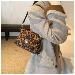 Detailed side view of a leopard print shoulder bag with silver metal clasp on a model