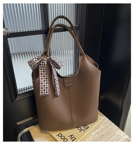 Detail of coffee brown pebble leather bucket bag with a checkered silk scarf accessory