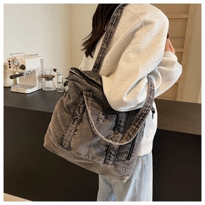 Detail of grey washed denim tote bag featuring metal snap pocket and broad shoulder strap