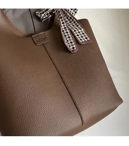 Close-up of brown lychee grain tote bag with a geometric silk scarf on the handle