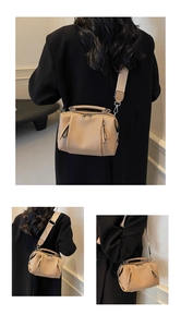 Close-up of beige Boston bag with lychee grain texture and wide canvas strap detail