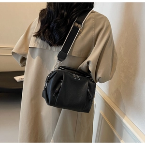 Detail of black lychee grain leather crossbody bag with stylish wide woven strap