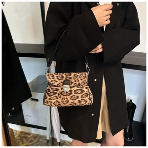 Detail of leopard print crossbody bag with silver buckle worn by a model in black suit