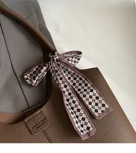 Detail of dark brown lychee leather bucket bag featuring decorative checkered silk scarf