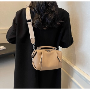 Detailed side view of khaki pleated leather crossbody bag with wide canvas shoulder strap