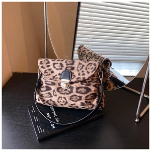 Close-up of vintage leopard print crossbody bag with golden clasp on decorative books