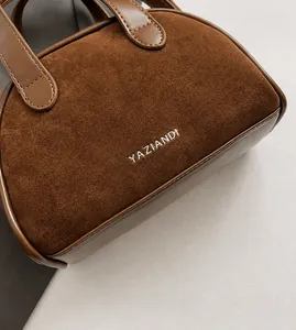 Detail van bruine crossbodytas met textuur, stikseldetails en het YAZIANDI-logo