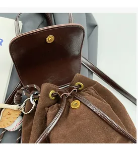 Détail du sac seau en daim marron foncé avec ferrures dorées et breloque baseball