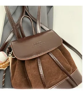 Détail de la texture contrastée en daim marron et cuir brillant sur un sac à dos stylé