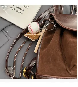 Détail d'un ensemble de breloques baseball avec gant et batte sur un sac à dos marron