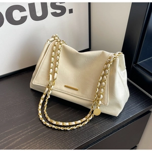 Macro detail of creamy white leather handbag featuring gold chain and metal bar ornament