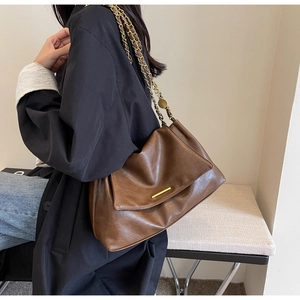 Détail du sac fourre-tout marron foncé avec boucle dorée et bandoulière en chaîne
