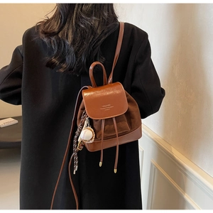 Détail d'un mini sac à dos vintage marron bicolore avec un pendentif balle de baseball