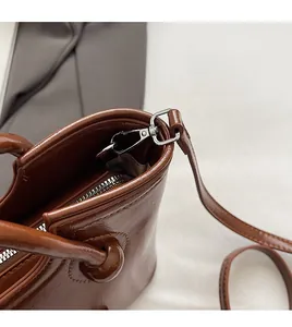 Gros plan du crochet amovible et de la poignée nouée sur un sac seau marron brillant